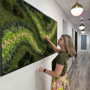 A black wooden frame filled with various shades of green moss in a swirl pattern.